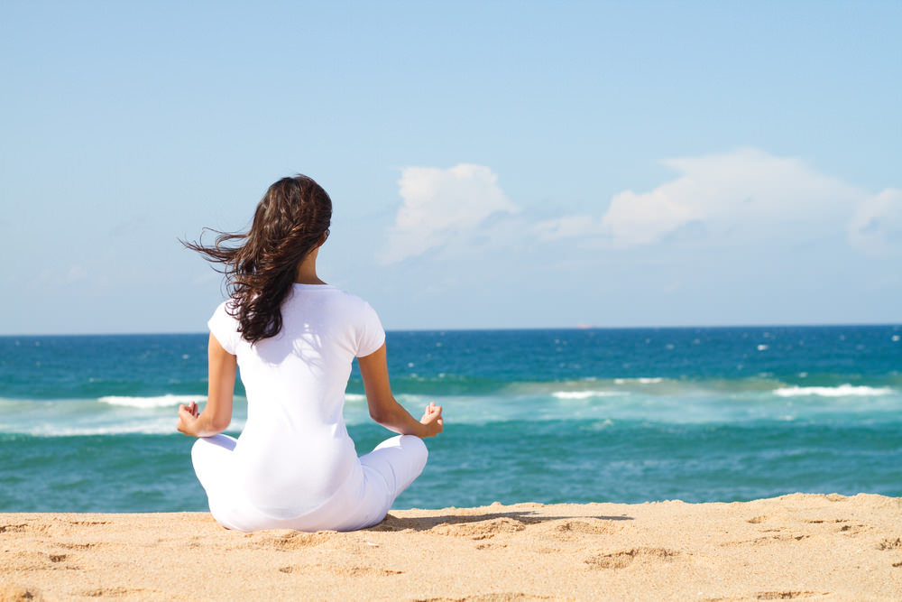woman meditating at beach